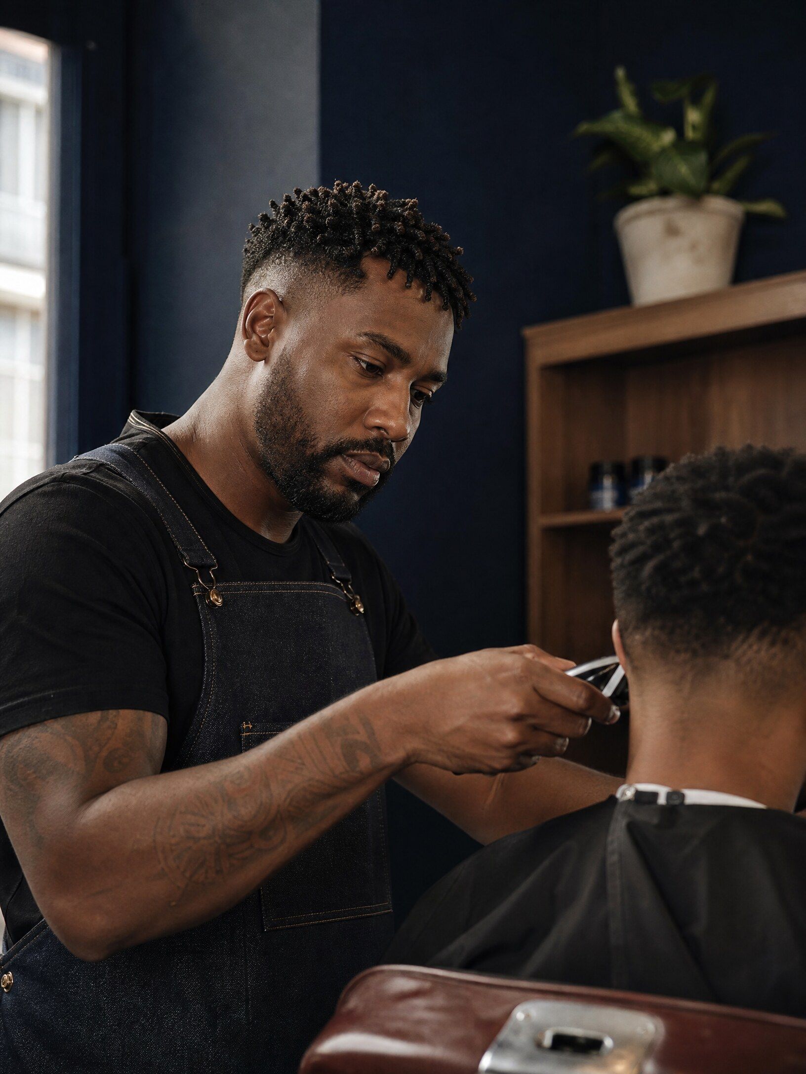 Barbeiro concentrado acertando o corte de um cliente na sua barbearia