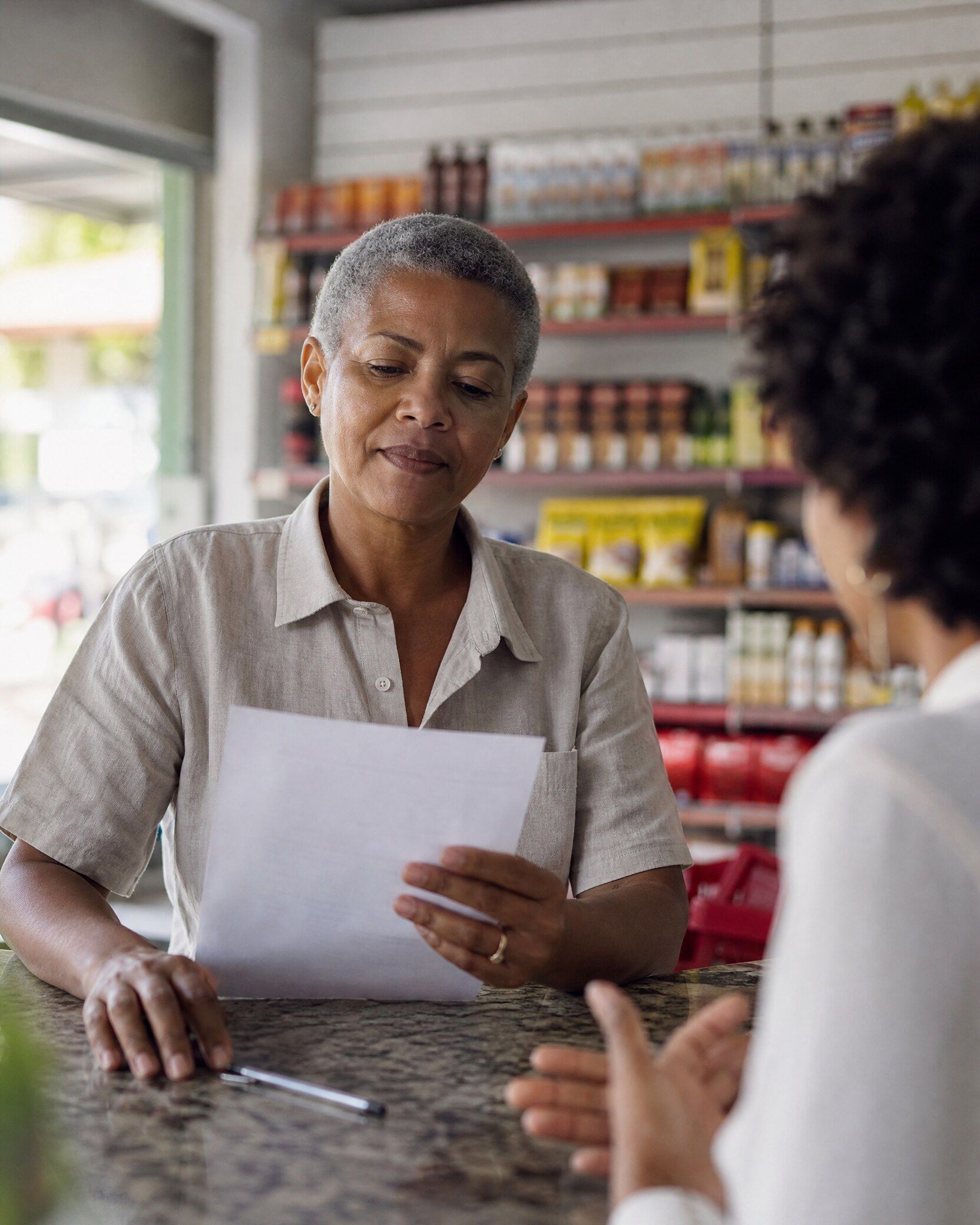 Comerciante lendo com atenção um documento no balcão da sua loja